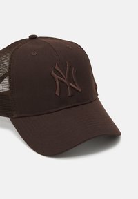 Brun caps med buet skygge, med brune nettsider og bakside. Brodert logo i en litt mørkere nyanse foran.
