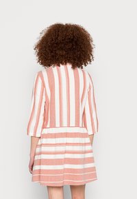 Vestido riscado em coral e branco, com corpete justo, mangas três quartos e uma saia rodada. Tecido texturizado com detalhe de renda na bainha.