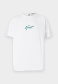White cotton t-shirt featuring “FRESH Groceries” in teal and yellow script. Classic crew neck and short sleeves, lightweight fabric.