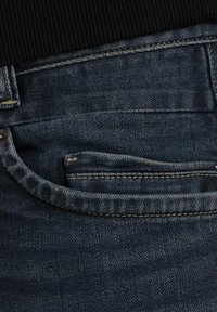 Jean en denim bleu foncé avec un détail de poche visible, présentant des coutures contrastées et une légère usure sur les bords, texture lisse.