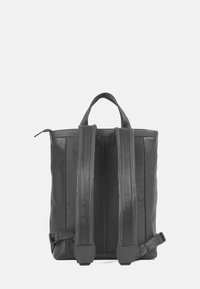 Svart läderryggsäck med två justerbara, vadderade axelremmar, ett handtag på toppen och en slät yta. Har en minimalistisk design och sömdetaljer.