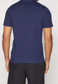 Camiseta de manga corta azul marino hecha de tela de algodón, con un cuello redondo y un ligero estiramiento. Diseño minimalista con líneas limpias.