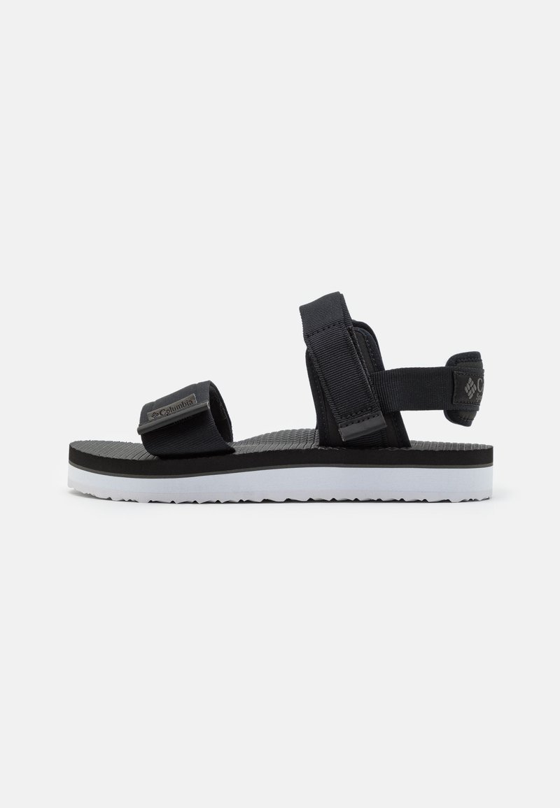 Sandalia deportiva negra con correas ajustables, plantilla texturizada y suela blanca con un sutil patrón de tracción. Logo de la marca en la correa.