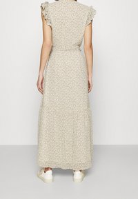 Maksimekko, jossa on kukkakuvio beigen ja pastellivärien sävyissä. Mallissa on röyhelöhihat ja vyötärönauhakiinnitys, valmistettu kevyestä kankaasta.