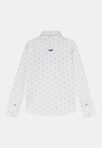 Biała koszula z długim rękawem w małe ciemnoniebieskie kwadratowe wzory, klasyczny kołnierzyk i mankiety na guziki. Zawiera logo na plecach oraz kontrastowe akcenty.