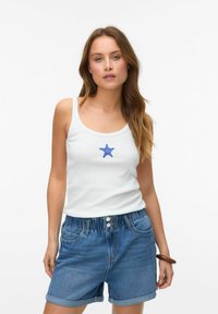 Witte tanktop met blauwe sterrenborduring, gecombineerd met blauwe denimshorts met een elastische tailleband en opgerolde manchetten.