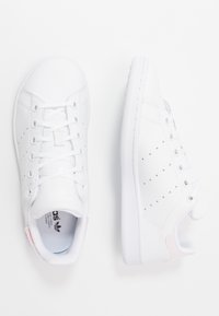 Vita lädersneakers med strukturerad yta, rund tå, snörning och perforerade detaljer på sidorna. Diskret rosa hälflik.