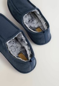 Tumedased sinised sussid, mis on valmistatud pehmest, sametiselt pehmest materjalist, halli karvase voodriga. Sussidel on õmmeldud pealne ja minimalistlik disain.