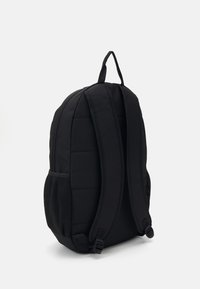 Svart ryggsekk med polstrede paneler, justerbare stropper og mesh-side lommer. Har et enkelt design og solide glidelåser.
