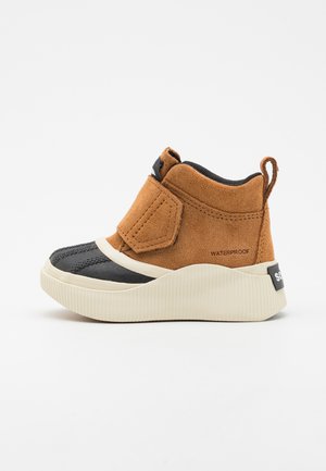 Waterproof ankle boots with a brown suede upper, black rubber toe cap, and a white ridged sole. Features a Velcro strap and rear pull tab.
