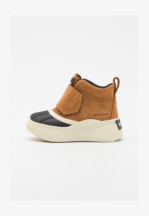 Waterdichte enkelboots met een bovenwerk van bruin suède, een zwarte rubberen teenkap en een witte geribbelde zool. Voorzien van een klittenbandsluiting en een lus aan de achterkant.