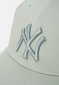 Světle zelená baseballová čepice s vyšitým logem NY ve sladěné barvě, s pevným korunkovým dílem a zakřiveným vizírem, pokryta texturovanou tkaninou.
