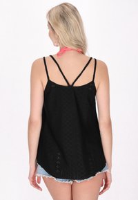 Top nero senza maniche con motivo intricato, spalline sottili regolabili e scollatura a barchetta. Abbinato a pantaloni shorts di denim.