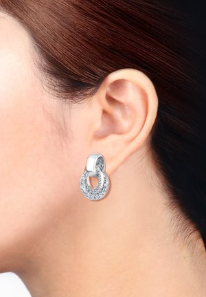 Silberne Ohrringe in Form von Reifen mit einem Doppelringdesign, verziert mit klaren Kristallen entlang der äußeren Kurve, mit einer polierten Oberfläche.