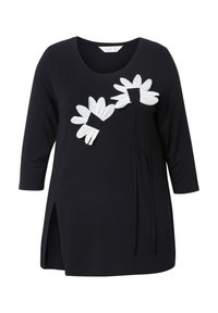 Maglietta nera a maniche lunghe con scollo rotondo, caratterizzata da due grandi applicazioni di margherite bianche e un dettaglio con spacco laterale. Tessuto morbido, design casual.