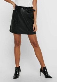 Mini-jupe en cuir noir avec une taille élastique, des passants de ceinture et des poches. Présente une texture lisse et un ourlet droit.