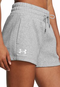 Pelēki kokvilnas šorti ar elastīgu jostu, auklu un sānu kabatām. Uz kājas atrodas baltais Under Armour logo.