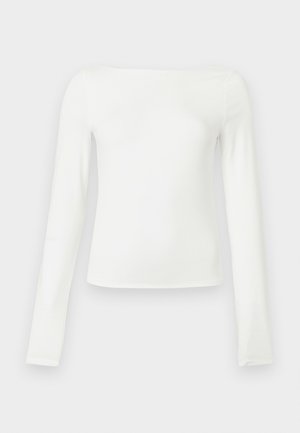 Haut blanc à manches longues, fabriqué en tissu lisse. Présente un col bateau et une silhouette ajustée, sans motifs ni accents visibles.