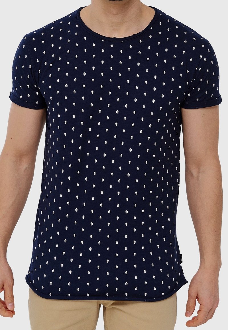 Camiseta azul marino hecha de tela suave, con un patrón de diamantes blancos repetitivo, mangas cortas y cuello redondo.