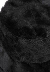 Cappello di pelliccia sintetica nera con una consistenza morbida e pelosa. Forma rotonda con un esterno liscio, caratterizzato da sottili variazioni di lucentezza e profondità.