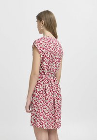 Floralna haljina u krem boji s ružičastim i zelenim uzorcima. Kap sleeves i naborani struk stvaraju opušteni kroj. Glatka, lagana tkanina.