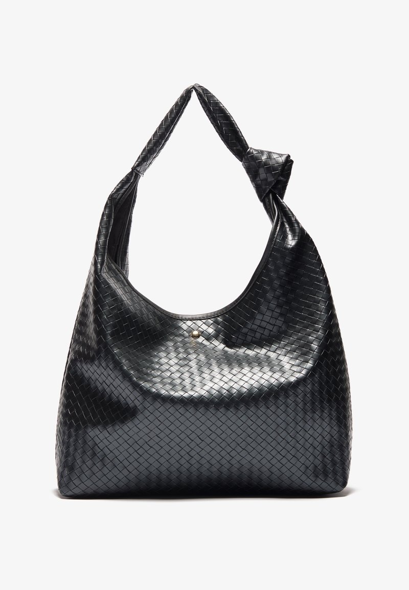 Sac à main en cuir noir avec une texture tissée et une sangle d'épaule nouée, présenté debout sur un fond clair uni.