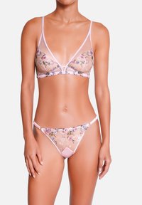Soutien-gorge transparent brodé de fleurs avec string assorti, présentant des accents rose pâle, des bretelles réglables et des textures délicates.