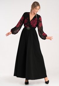 Czarna maxi sukienka z przezroczystą, kwiatową narzutą, z długimi bufkami, głębokim dekoltem w serek oraz paskiem w talii z podwójnymi okrągłymi akcentami.