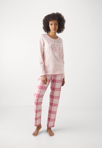 Långärmad rosa topp med broderi av blommiga hjärtan, ihopparad med rosa och vita rutiga pyjamasbyxor. Mjuk bomullstyg. Inga synliga mönster på ärmarna.