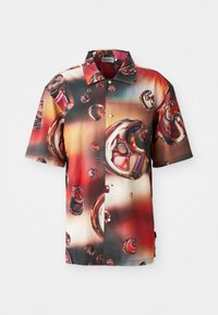 Chemise à manches courtes en tissu brillant, présentant un design abstrait éclatant de bulles rouges et brunes sur un fond dégradé. Boutonnage sur le devant.