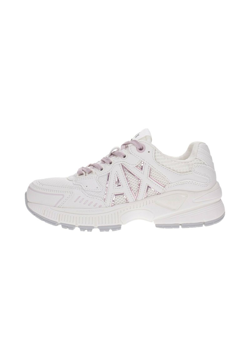 Zapatilla deportiva blanca con acentos morados, paneles de malla y superficie texturizada. Cuenta con una suela gruesa y un logotipo prominente en el lateral.