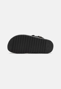 Suola di scarpa nera con una superficie texturizzata, caratterizzata da scanalature orizzontali e un bordo leggermente rialzato. Materiale in gomma resistente per una migliore aderenza.