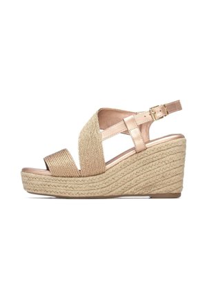 Sandalias de cuña con suela de fibra natural tejida y parte superior metálica en oro rosa. Presentan tiras cruzadas con cierre de hebilla.