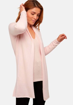 Gilet rose clair avec ouverture sur le devant, fabriqué en tissu doux. Il possède des manches longues et une coupe décontractée, complétant un look superposé.