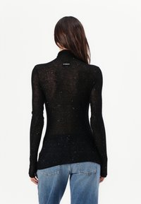 Svart langermet topp med høy krage, laget av lett materiale. Designet har spredte sølvdetaljer og en merkeetikett på baksiden.