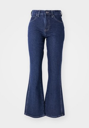 Dark blue flared jeans made from denim, featuring a high waist, front button closure, and contrasting white stitching along the seams.