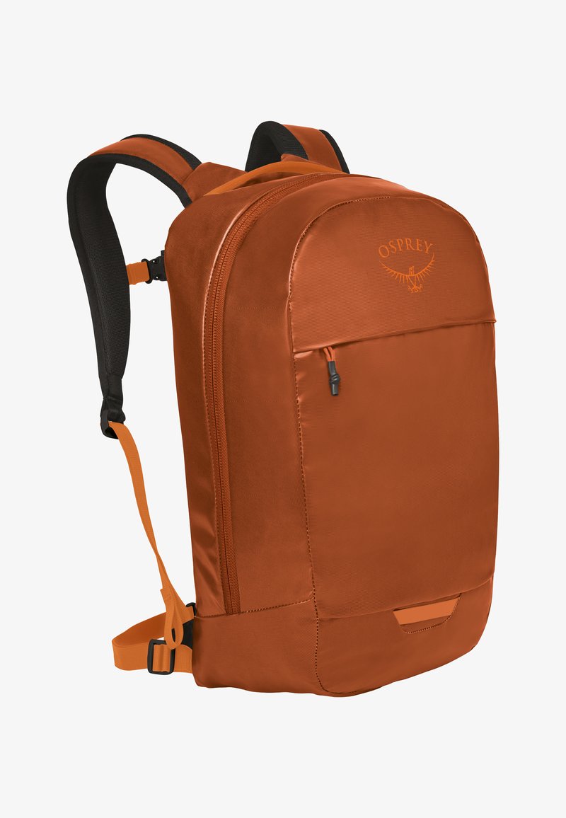 Sac à dos en tissu orange avec des sangles noires rembourrées et ajustables, une poche zippée à l'avant et un dessus arrondi. Présente un détail de logo à l'avant.