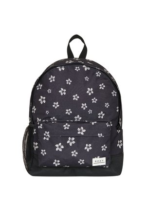 Mochila de tela negra con patrón floral blanco, que cuenta con un bolsillo frontal, un bolsillo lateral de malla y un asa superior para llevar. Incluye una etiqueta de la marca Roxy.