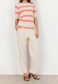Lightweight ribbed sweater with horizontal coral stripes, paired with beige tapered trousers. Brown heeled sandals complete the outfit.