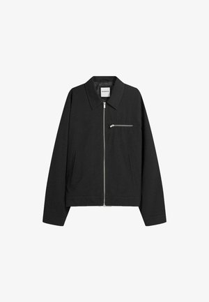 Black zip-up jacket made of soft fabric, featuring a classic collar, long sleeves, side pockets, and a small chest pocket with a zipper.