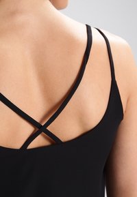 Schwarzes ärmelloses Top mit dünnen Trägern, die sich am Rücken kreuzen, glatter Textur und einer taillierten Passform, die den Schulterbereich betont.