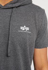 Szara bluza z kapturem ze sznurkiem, z białym logo na piersi. Wykonana z miękkiego materiału o luźnym kroju i krótkich rękawach.