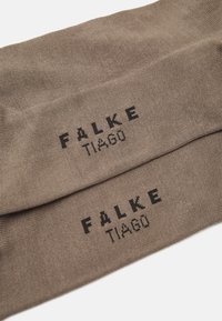 Braune Baumwollsocken mit dem Logo "FALKE TIAGO" in schwarzem Stickdesign. Glatte Textur mit einem dezenten Glanz.