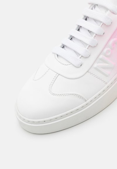 Baskets blanches en cuir avec des lacets plats blancs, bout rond, logo gaufré sur la languette et une épaisse semelle en caoutchouc. Détail dégradé rose subtil.