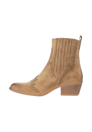 Bottine en daim marron clair avec talon bas superposé, surpiqûres décoratives, rayures verticales perforées et accents de clous en laiton le long des bords.