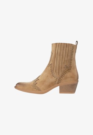 Enkellaarsje in tan suède met lage opgestapelde hak, decoratieve stiksels, geperforeerde verticale strepen en koperen studs langs de randen.