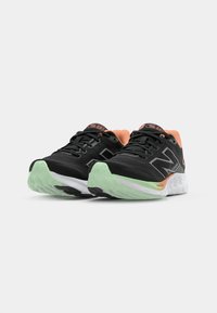 Black athletic shoes with a textured upper, featuring orange accents, a white midsole, and a green outsole, designed for comfort and support.