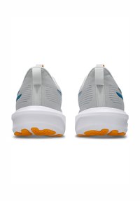 Grå nätlöparskor med vita sulor och orange gummidetaljer. Bakifrån syns dragflik och blå sidologotyper, designade för komfort och stöd.