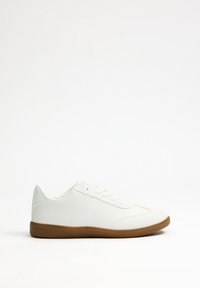 Zapatillas sintéticas blancas con un acabado suave, que cuentan con una suela de goma y un diseño de cordones. Destacan por sutiles detalles de costura en los laterales.