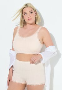 Bralette en coton rose clair et shorts assortis avec bord en dentelle. Le bralette présente un design froncé ; les shorts ont des côtes verticales et un petit nœud décoratif.